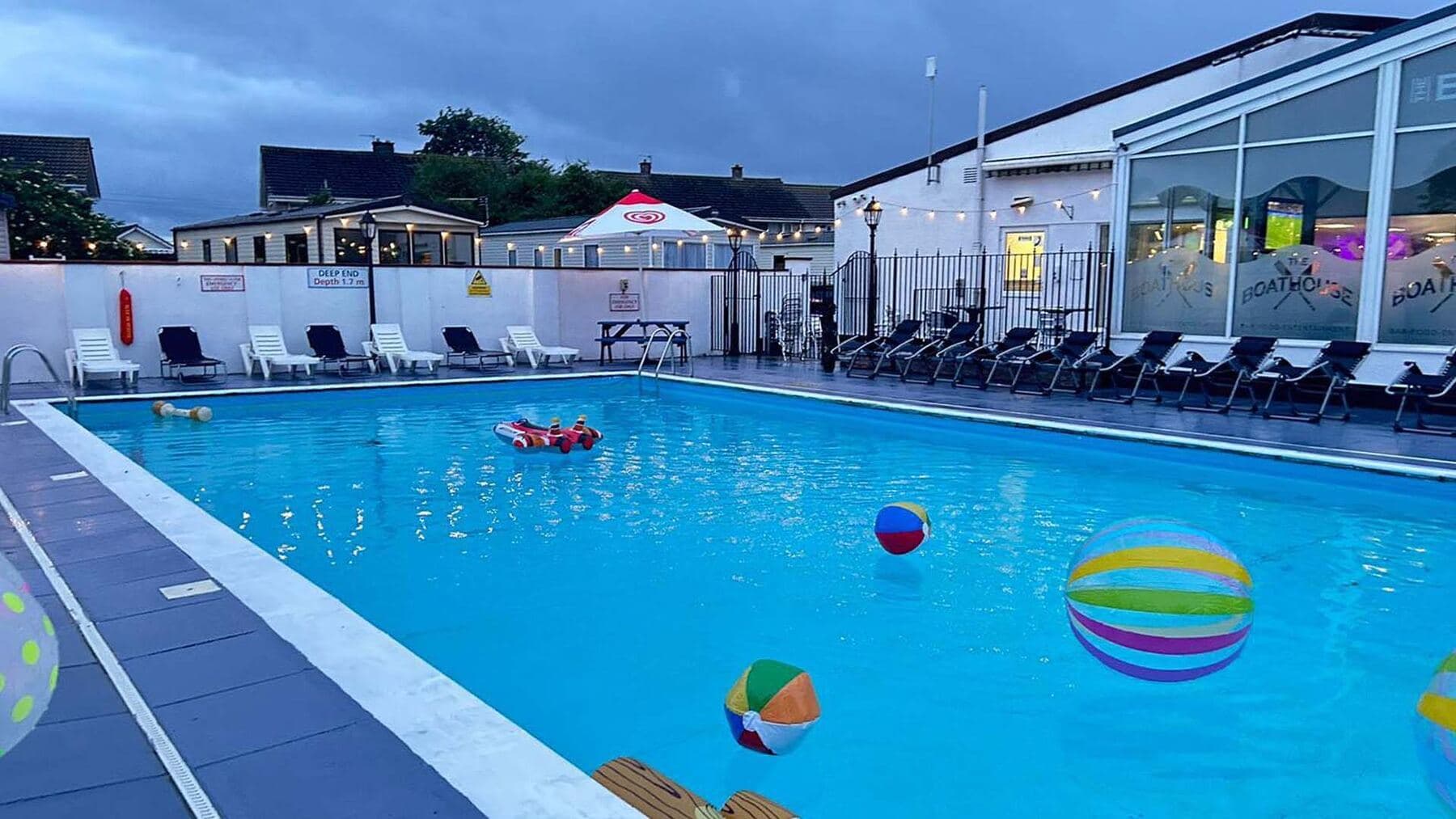 The outdoor pool at the holiday park on a sunny afternoon, inflatables on the water
