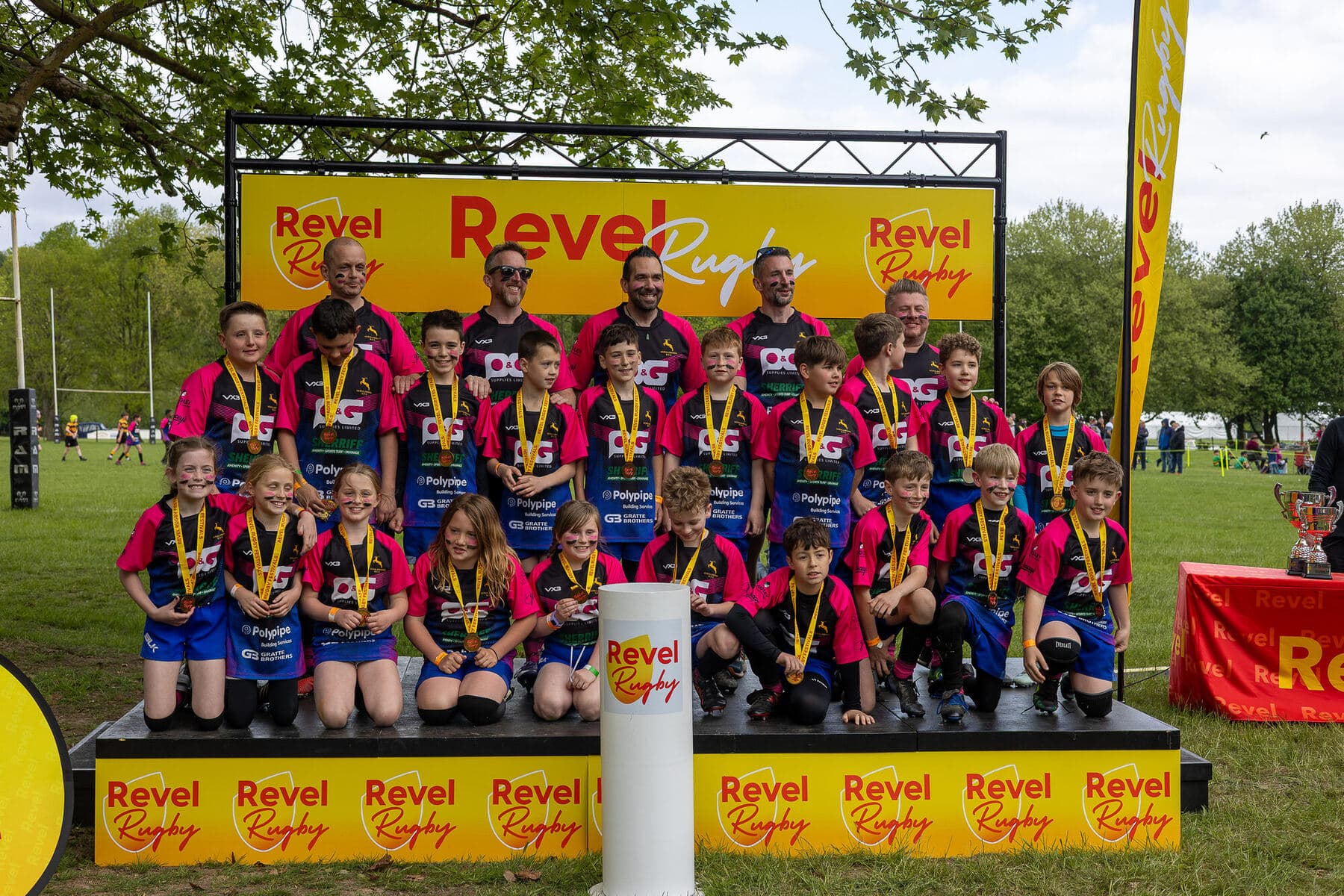 A whole club squad and their coaches lined up on the stage with medals and a trophy