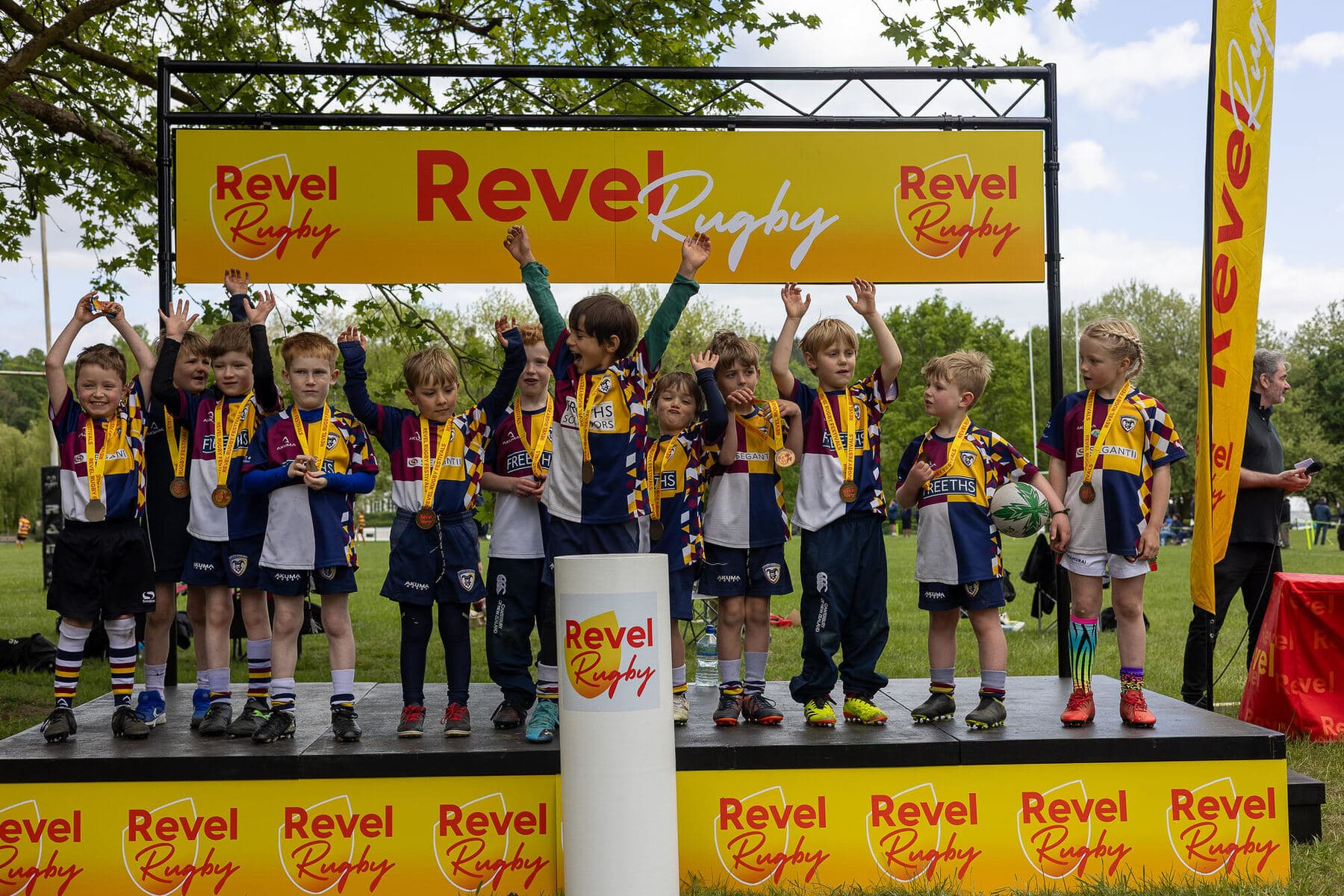 A whole team on the Revel Rugby stage with medals round their necks and arms in the air