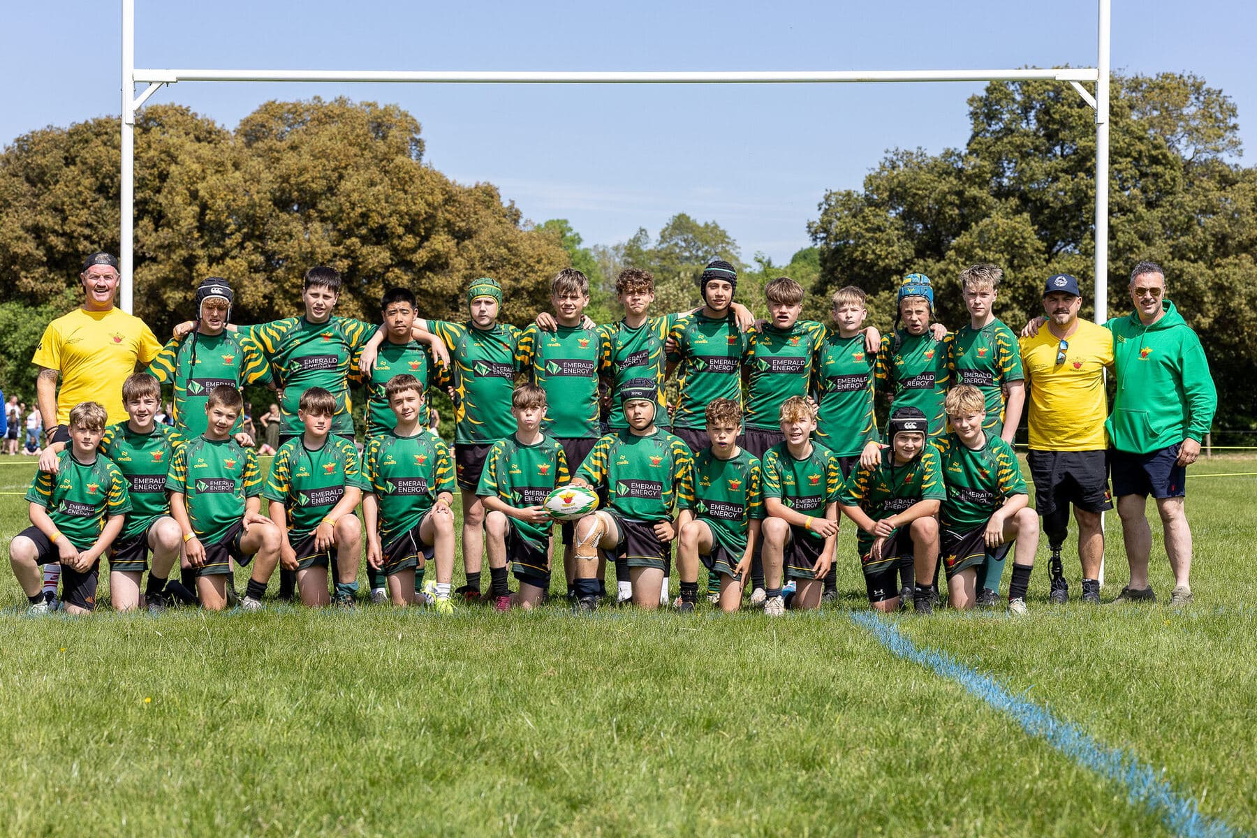 A whole club squad in green kit lined up in front of the posts in bright sunshine