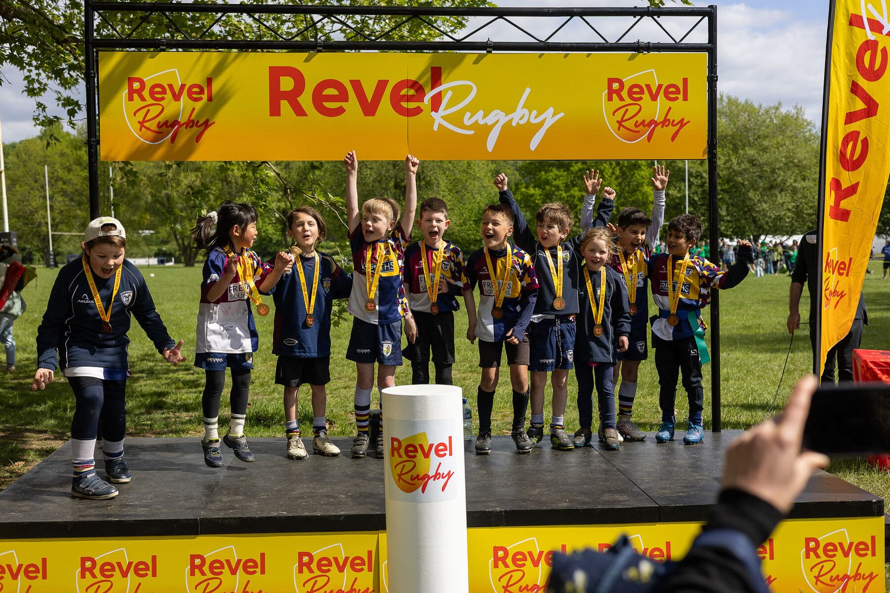 A team on the podium with medals round their necks and arms raised in celebration