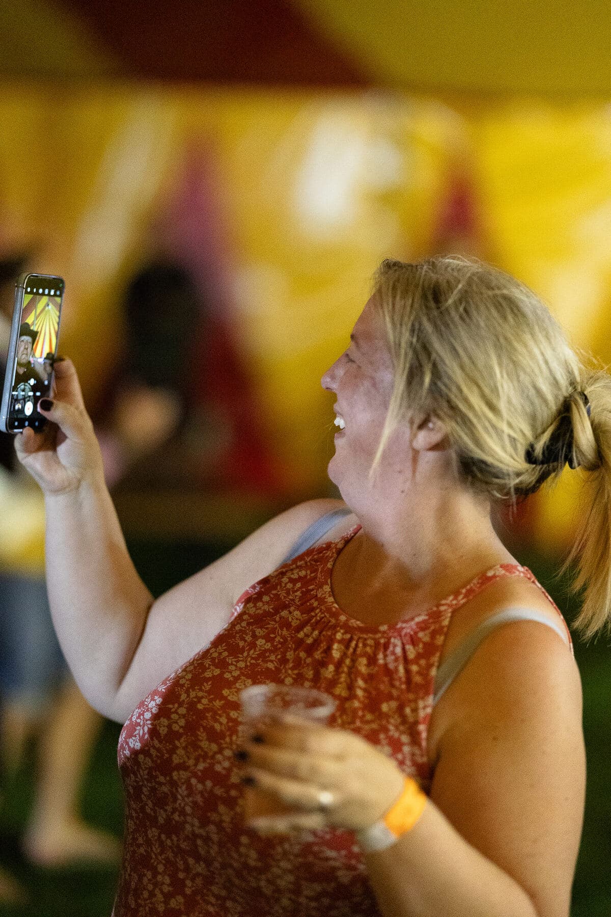 A mum filming the presentation on her phone, smiling, in front of the Revel Rugby stage