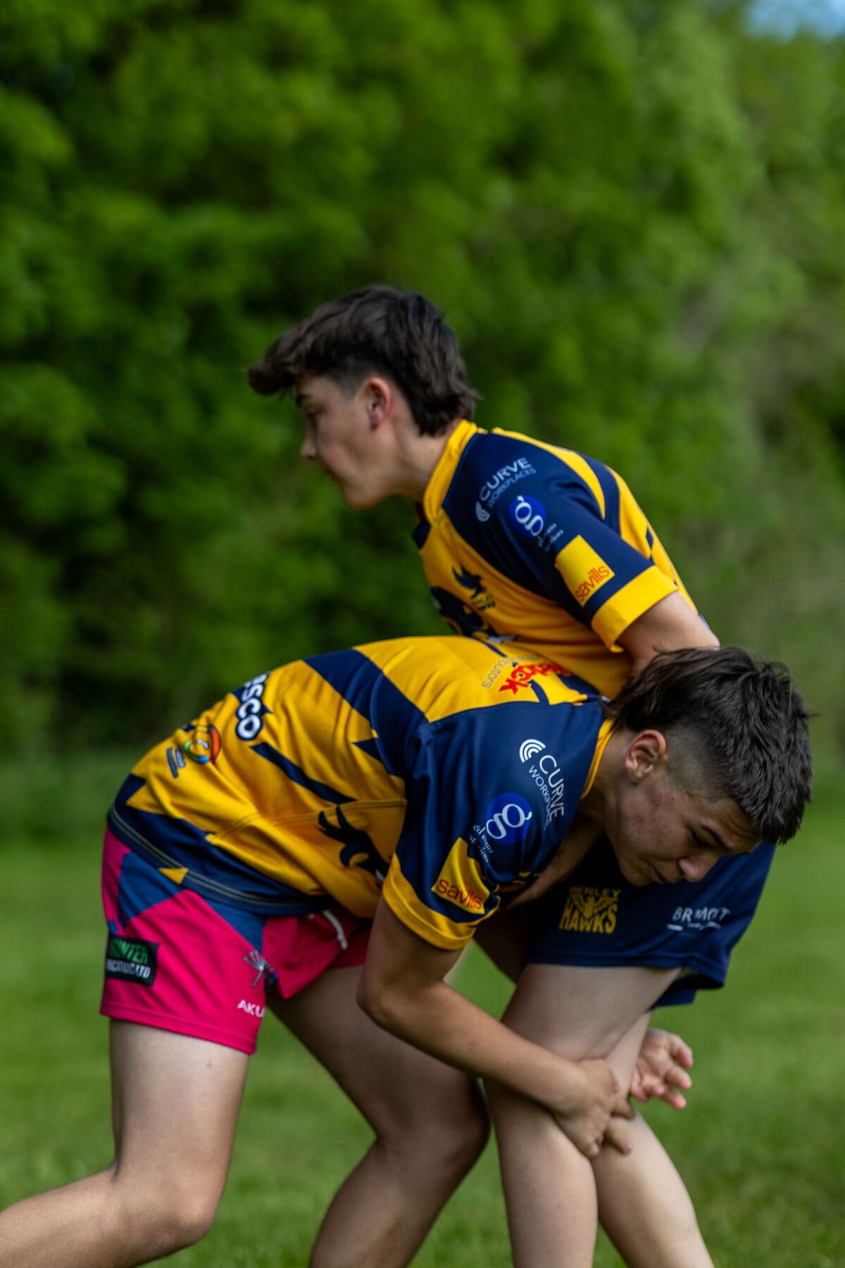Two teenage players locked together in contact during a tour fixture